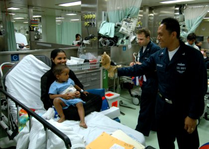 US Navy 060701-N-3532C-032 Navy Hospital Corpsman 3rd Class Ronald Bayaca of San Diego, Calif., entertains a young patient aboard the U.S. Military Sealift Command hospital ship USNS Mercy (T-AH 19)