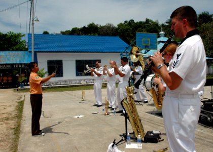 US Navy 060812-N-3714J-119 A student from the Tarakan School conducts the U.S. Navy Show Band embarked with the Medical Treatment Facility aboard the U.S. Naval hospital ship USNS Mercy (T-AH 19) during a performance at the sch photo