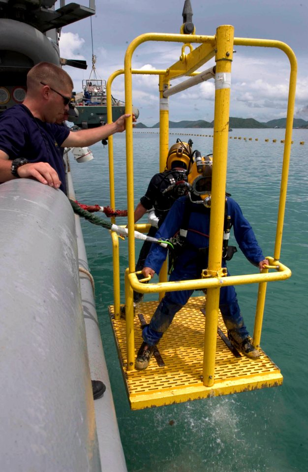 US Navy 060621-N-9851B-006 Royal Thai Navy diver Ensign Mongkol Boontun and U.S. Navy diver Damage Controlman 2nd Class John Marshall are raised from the water on a diving stage from rescue and salvage ship USS Salvor (ARS 52)