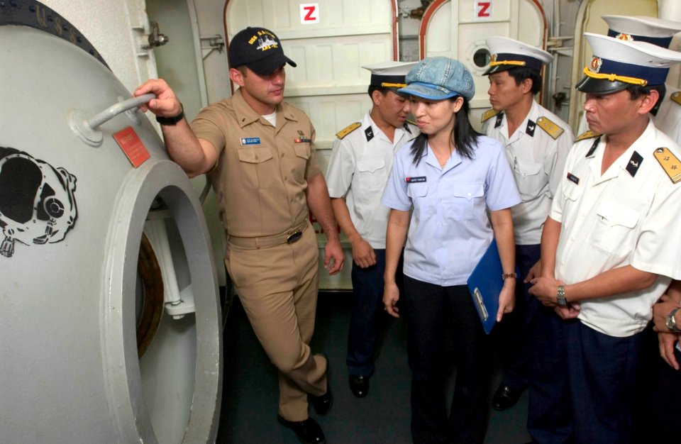 US Navy 060704-N-9851B-002 Lt.j.g. Robert Gillenwater, explains to visitors from the Navy division of the People's Army of Vietnam (PAVN) the purpose of the diver's decompression chamber