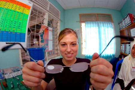 US Navy 060814-N-6501M-021 A patients view of Air Force Capt. Jennifer Owen, a native of Birmingham, Ala., helping try on a pair of reading glasses in the optometry clinic at the Mamburungan outreach site, located on the island photo