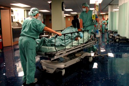 US Navy 060823-N-1577S-013 Medical staff attached to the Medical Treatment Facility aboard the Military Sealift Command (MSC) hospital ship USNS Mercy (T-AH 19) transport a patient into an operating room