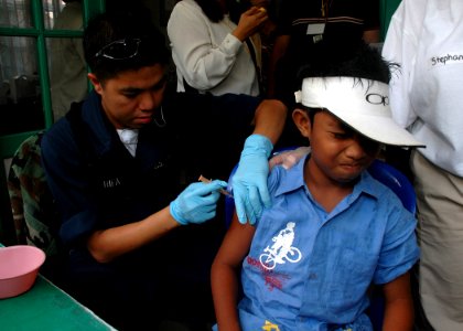 US Navy 060812-N-3931M-072 Navy Hospitalman Renie Charifa embarked with the Medical Treatment Facility aboard the Military Sealift Command (MSC) hospital ship USNS Mercy (T-AH 19), administers an immunization shot to a local ch photo