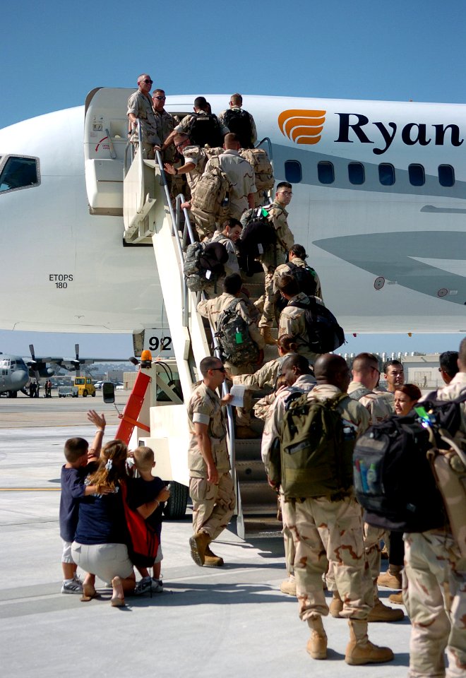 US Navy 060824-N-4774B-165 Gunner's Mate 2nd Class Joseph Jeffcott waves goodbye to his wife and children as he boards a commercial airplane with Sailors from Naval Coastal Warfare Squadron Three Four (NCWRON 34) bound fo