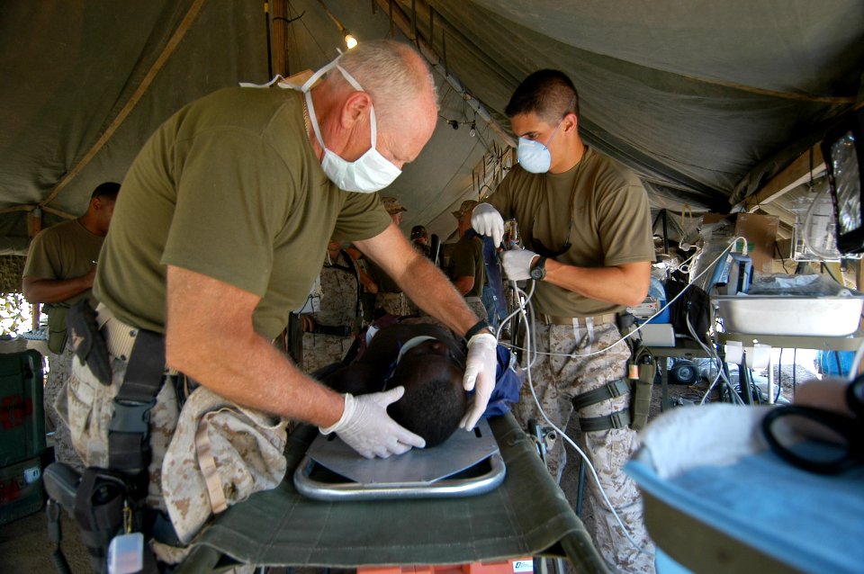 US Navy 060818-N-0411D-079 U.S. Navy Cmdr. Dr. Warren Gilbert, left, of Reno, Nev., examines a patient with a mock head during field training