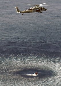 US Navy 060824-N-8547M-016 A search and rescue swimmer (SAR) is hoisted out of the water by an MH-60S Seahawk assigned to Helicopter Sea Combat Support Squadron Two Six (HSC-26), during combined training with SAR swimmers
