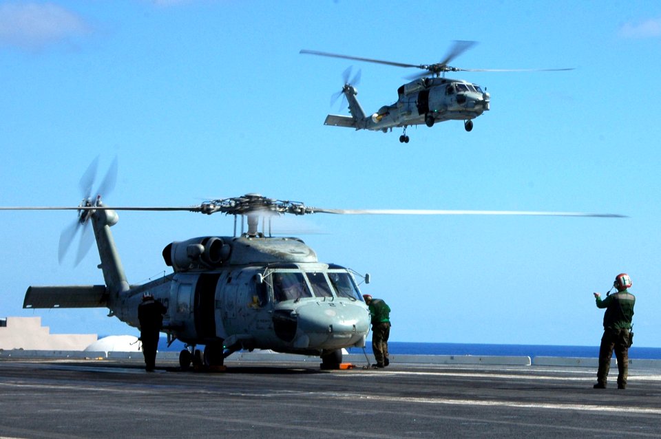 US Navy 060821-N-6106R-177 A flight deck Sailor from Helicopter Antisubmarine Squadron Fourteen (HS-14) directs an HH-60H Seahawk into place prior to shutting down on the flight deck of USS Kitty Hawk (CV 63)