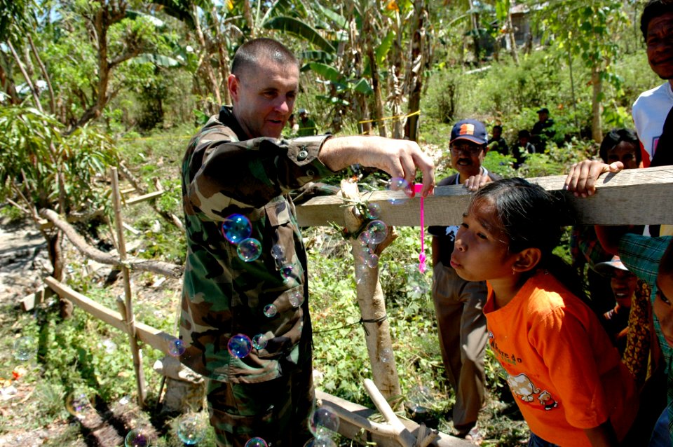 US Navy 060825-N-3714J-066 U.S. Navy Cmdr. Donald Fix of Pittsburg, Pa., attached to the Medical Treatment Facility aboard the Military Sealift Command hospital ship USNS Mercy (T-AH 19), lets a child blow bubbles