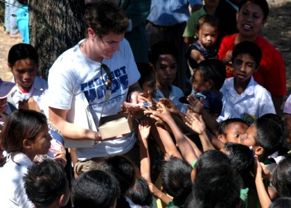 US Navy 060824-N-9076B-134 Project Hope Volunteer Craig Jacques hands out pencils to children during a medical outreach at the Batakte Health Center as part of the Military Sealift Command hospital ship USNS Mercy (T-AH 19) vis