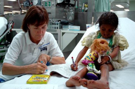 US Navy 060828-N-1577S-037 Project HOPE volunteer Annie Mannino embarked with the Medical Treatment Facility aboard the Military Sealift Command hospital ship USNS Mercy (T-AH 19), colors with a patient in casualty receiving ar