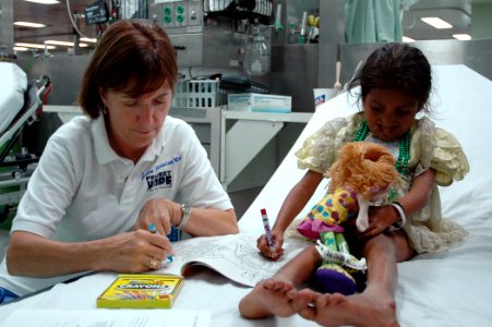 US Navy 060828-N-1577S-037 Project HOPE volunteer Annie Mannino embarked with the Medical Treatment Facility aboard the Military Sealift Command hospital ship USNS Mercy (T-AH 19), colors with a patient in casualty receiving ar photo