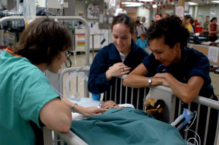 US Navy 060830-N-9076B-239 Navy Lt. Tara Collins, left, Hospitalman Kaylah Stubbs, center, and Lt. jg. Cathrine Soteras, comfort a small baby in the Intensive Care Unit photo