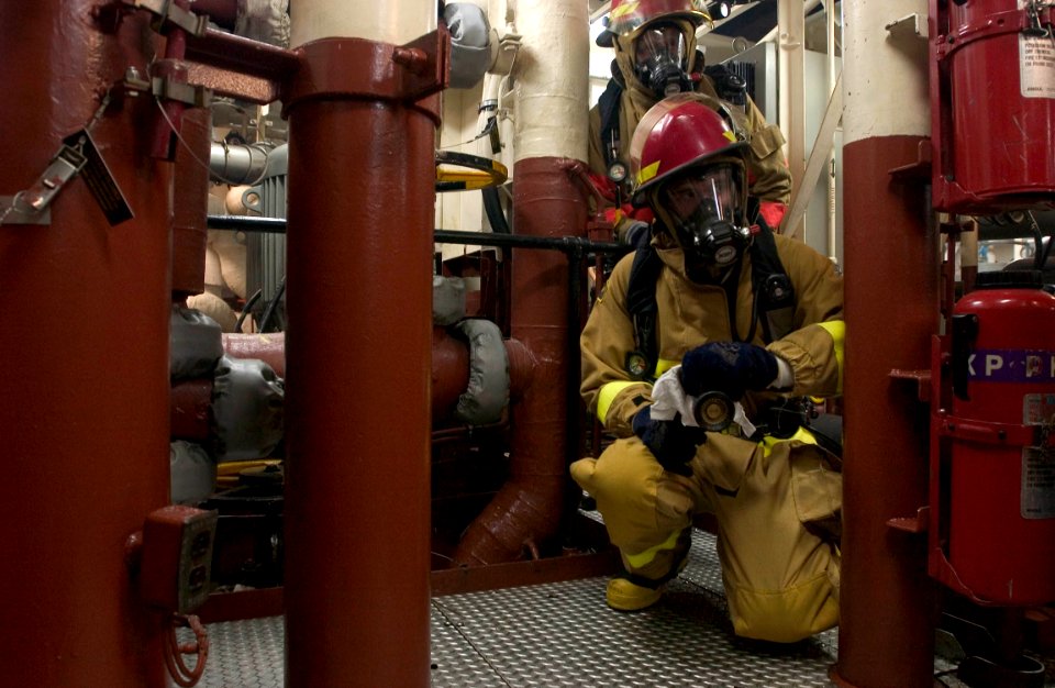 US Navy 060830-N-9851B-004 Gas Turbine Systems Technician Fireman Joshua Cox watches for a reflash during a simulated fire drill during a General Quarters drill in the number Two Main Machinery Room