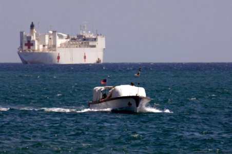 US Navy 060829-N-6501M-010 The Military Sealift Command hospital ship USNS Mercy (T-AH 19) sits on the horizon, as one of Mercy's two transport boats approaches the pier to drop off patients returning after receiving health car