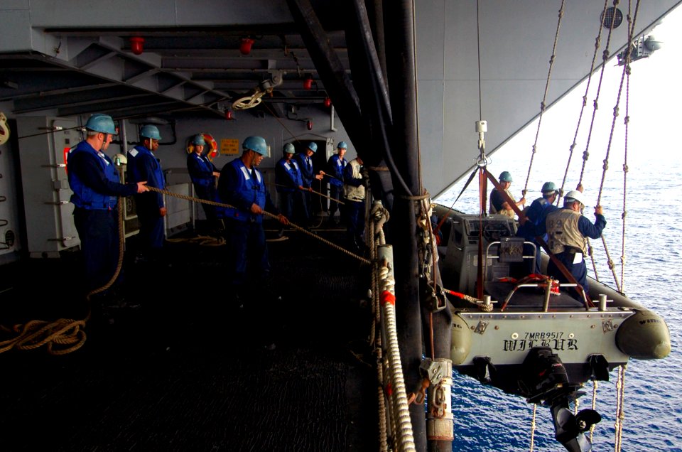 US Navy 060829-N-8604L-077 USS Kitty Hawk (CV 63) Deck Department Sailors keep a Rigid Hull Inflatable Boat (RHIB) steady while it is hoisted from the water after participating in a small boat in distress and rescue drill