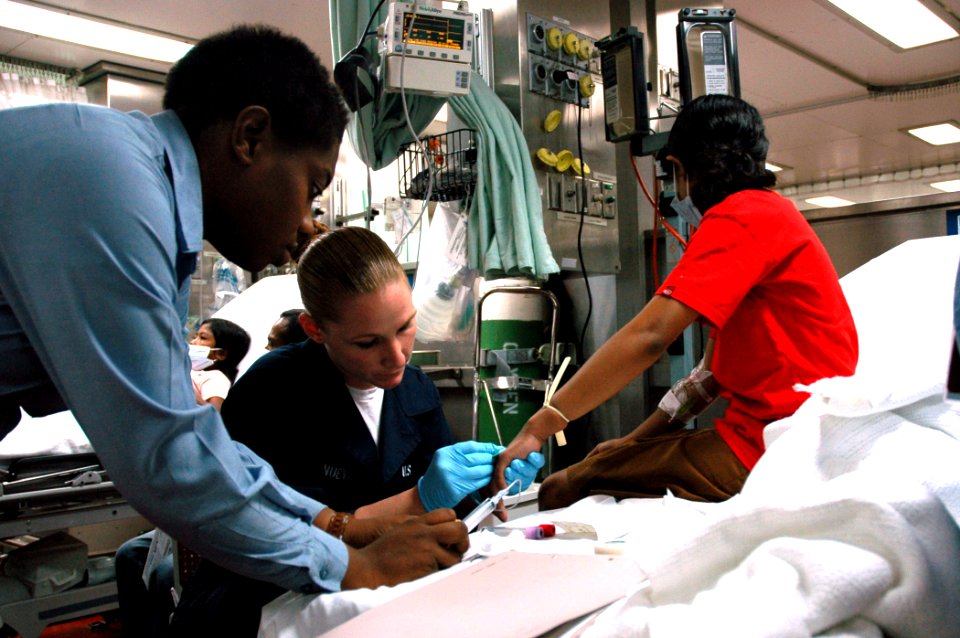 US Navy 060829-N-1577S-004 Navy Hospitalman Laneice Wright and Hospitalman Jossey Villanueva assigned to the Medical Treatment Facility aboard the Military Sealift Command hospital ship USNS Mercy (T-AH 19), draw blood from a p