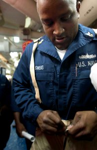 US Navy 060901-N-9851B-001 Operations Specialist 1st Class LaMont Owens dons an Advanced Chemical Protective Garment (ACPG)