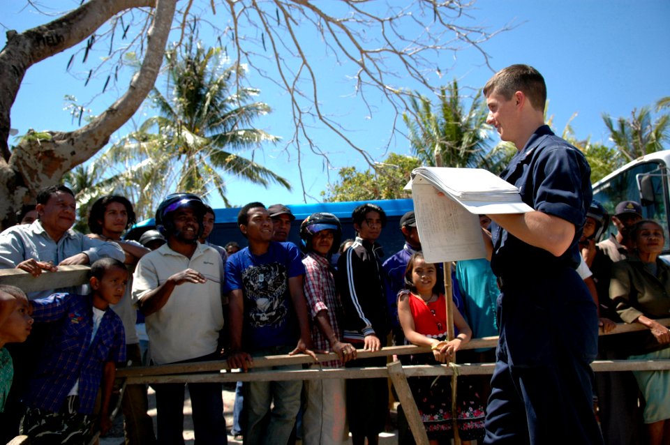 US Navy 060825-N-3714J-061 Navy Religious Programs Specialist 3rd Class Steven Kennan of Auburn, Calif., attached to the Military Seallfit Command hospital ship USNS Mercy (T-AH 19), shows flash cards to local residents to help