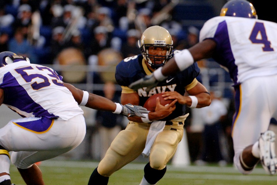 US Navy 060902-N-9693M-007 U.S. Naval Academy Quarterback Brian Hampton rushes for yardage and tries to elude East Carolina defenders Scotty Robinson, 53, and Kyle Chase in the first half of play at Navy - Marine Corps Memorial