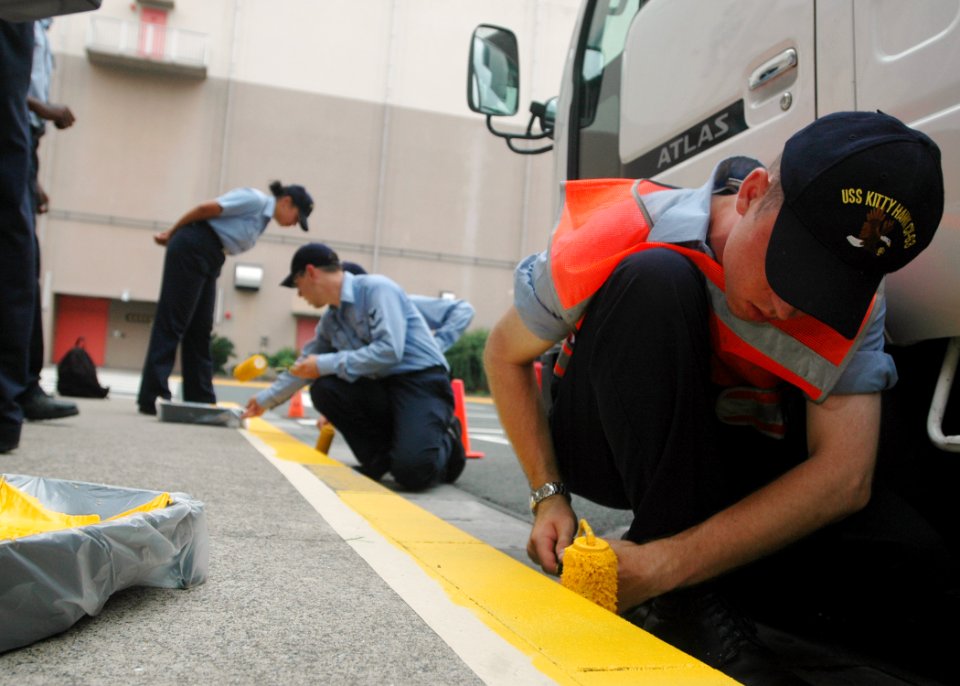 US Navy 060830-N-1332Y-010 Aviation Ordnanceman Airman Apprentice Sean Santosuosso from Boston, Mass., and fellow Sailors assigned to the aircraft carrier USS Kitty Hawk (CV 63), apply fresh yellow paint to street curbs