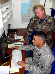 US Navy 060906-F-8479N-005 Lt. Col. Kelli Pohlman, from J-4 Logistics Directorate, discusses logistics reporting with J-4 Logistics executive officer U.S. Army Lt. Col. Neil Higgins aboard the amphibious command ship USS Mount