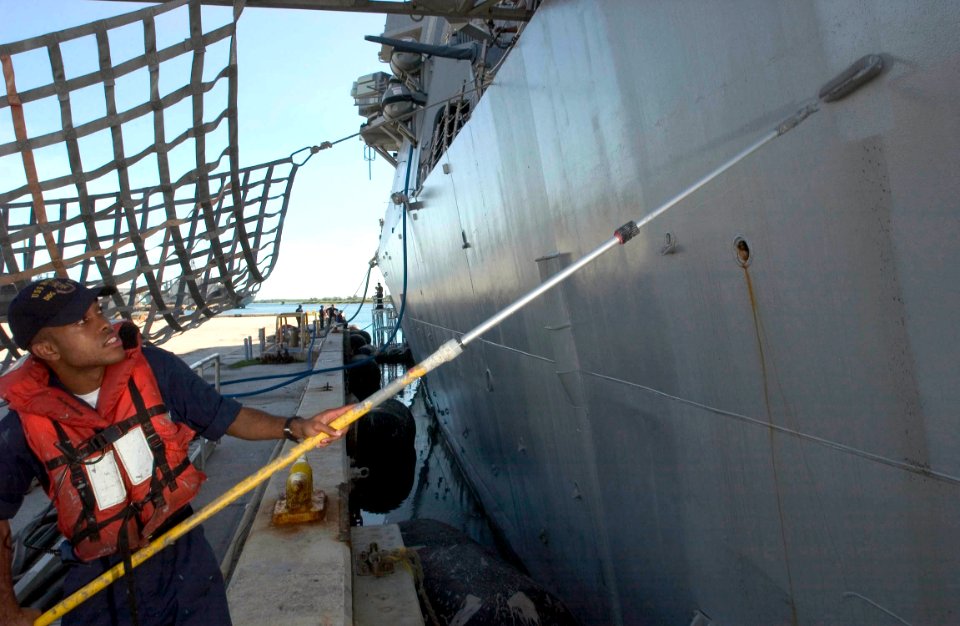 US Navy 060904-N-9851B-006 Fire Controlman 3rd Class Vernon McDaniel, assigned to the guided missile destroyer USS Hopper (DDG 70), paints the side of the ship during a port visit to Guam photo