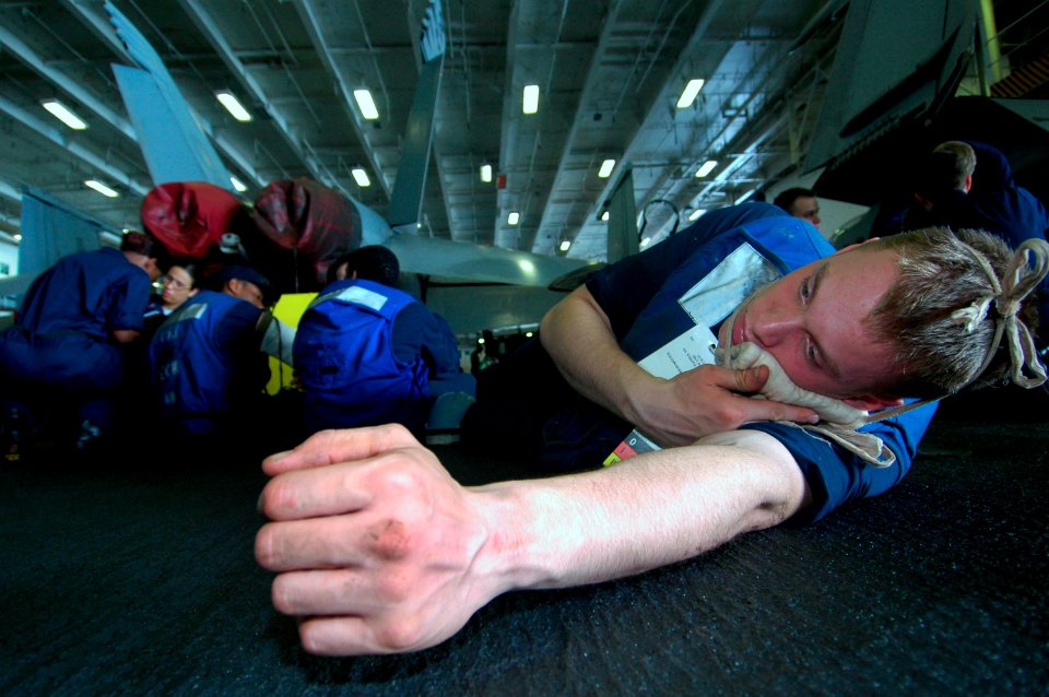 US Navy 060830-N-8604L-373 Seaman Richard Macken lies on the hangar bay deck with a simulated jaw injury, during a mass casualty drill aboard the conventionally powered aircraft carrier USS Kitty Hawk (CV 63)
