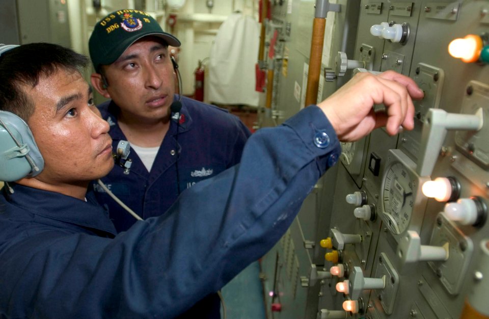 US Navy 060907-N-9851B-003 Electrician's Mate Fireman Rafael Campano simulates the control of an electrical switch board under the supervision of Gas Turbine Systems Technician Electrical 1st Class Victor Ponce