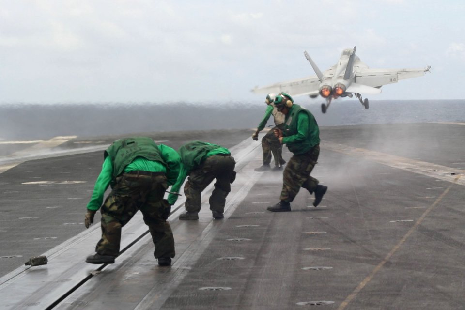 US Navy 060831-N-8591H-149 Flight deck crewmen rush to one of USS Kitty Hawk (CV 63) four steam-powered catapults to tighten track buttons after an F-A-18 hornet takes off from during flight operations