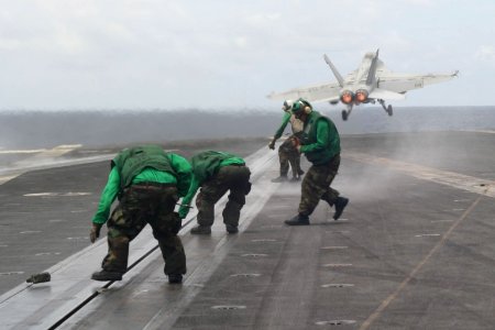 US Navy 060831-N-8591H-149 Flight deck crewmen rush to one of USS Kitty Hawk (CV 63) four steam-powered catapults to tighten track buttons after an F-A-18 hornet takes off from during flight operations
