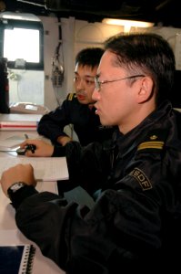 US Navy 061113-N-5387K-064 Japanese Maritime Self-Defense Force (JMSDF) officers Lt. Cmdr. Kimihiro Ichiyanagi and Lt. j.g Mitsuhiro Matsumoto discuss shipboard operations on the flag bridge aboard USS Kitty Hawk (CV 63) during