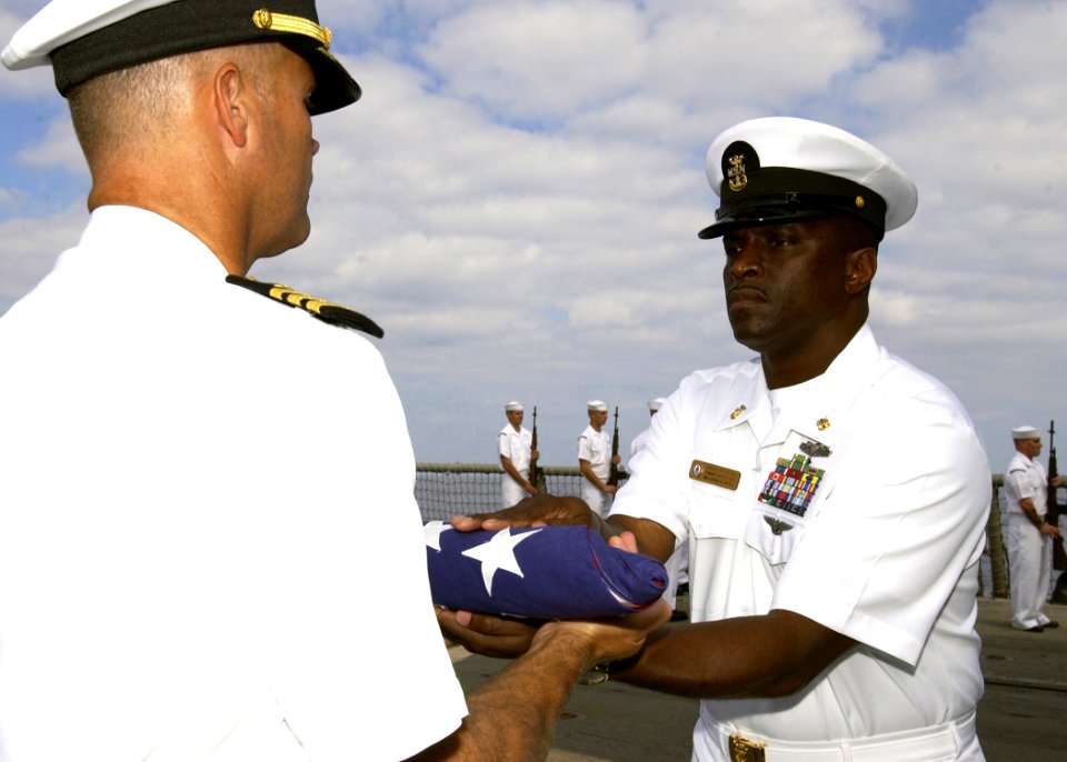 US Navy 061110-N-3285B-065 The Command Master Chief Billy Hill, assigned to the Oliver Hazard Perry-class frigate USS Stephen W. Groves (FFG 29) hands a flag to the ship's Commanding Officer, Cmdr. Jon Kreitz, during a burial a