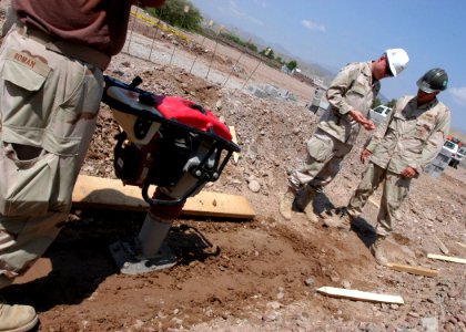 US Navy 061109-N-1328C-075 Commander 1st Naval Construction Division, Rear Adm. Robert Phillips (Right), discusses dirt samples with Steel Worker 1st Class Dennis Ryan, and a member of Naval Mobile Construction Battalion Five (