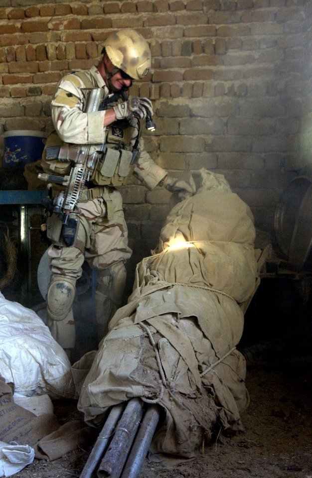 US Navy 061120-F-7426P-297 U.S. Navy Explosive Ordnance Disposal (EOD) Technician 1st Class Travis J. Schellpeper systematically searches outside a residence for any evidence of a weapons cache photo