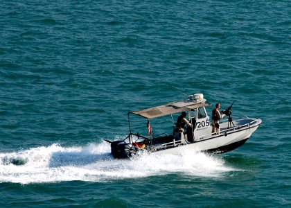 US Navy 061110-N-8547M-021 A harbor patrol boat unit assigned to Naval Security Force Bahrain escorts amphibious assault ship USS Saipan (LHA 2) away from the pier following a brief port visit and offload of mine sweeping equip