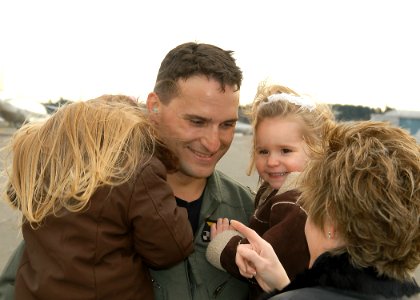 US Navy 061117-N-6247M-008 Lt. Cmdr. Chad Largess greets his daughters and wife after returning home from deployment photo