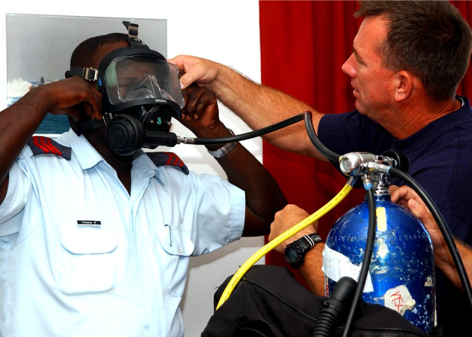 US Navy 061110-N-4205W-003 Senior Chief Navy Master Diver Gene McDaniel, assigned to Mobile Diving and Salvage Unit One (MDSU-1) Detachment 5, based in Pearl Harbor, Hawaii, explains the Mk 20 full face mask to Seychelles Coast