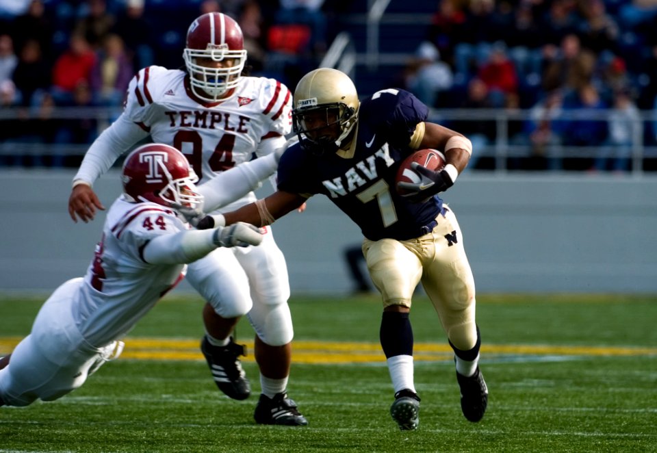 US Navy 061118-N-0696M-152 Naval Academy Midshipmen running back Reggie Campbell stiff-arms Temple University Owls linebacker Walter Mebane at Navy-Marine Corps Memorial Stadium