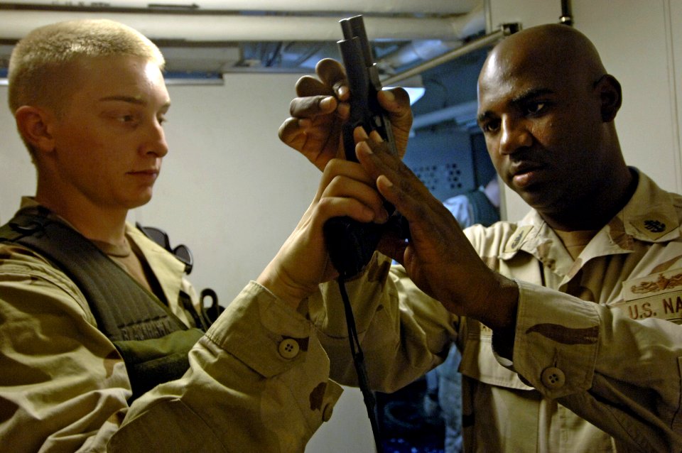 US Navy 061118-N-8148A-271 U.S. Navy Gunner's Mate Seaman Randy Barnes, left, assigned to Mobile Security Squadron Three (MSS-3), shows Chief Master at Arms Cephia Batson that his 9mm pistol is clear and safe to holster during