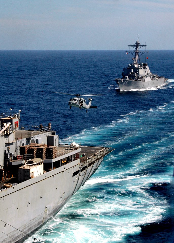 US Navy 061127-N-8547M-054 An MH-60s helicopter prepares to land on the flight deck of guided-missile destroyer USS Benfold (DDG 65) while pulling alongside Military Sealift Command (MSC) fast combat support ship USNS Supply (T