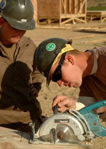 US Navy 061125-N-6889J-018 Mandy Lewis, a steel worker assigned to Naval Mobile Construction Battalion Seven Four (NMCB-74), observes Kevin Yaksich, a utilitiesman, as he cuts the frames for steps at Camp Ramadi
