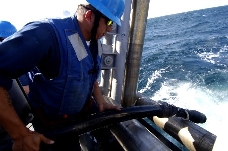 US Navy 061203-N-5555T-003 U.S. Navy Mineman 3rd Class Rene Gonzales places a magnetic coax cable in the sea to pulsate electricity, sweep and destroy mines during a mine countermeasure exercise aboard the USS Ardent (MCM 12)