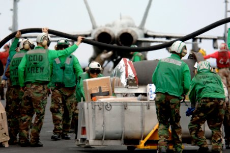 US Navy 061201-N-6106R-081 The carrier on-board delivery (COD) crew from Fleet Logistics Support Squadron Three Zero (VRC-30) lifts a fuel hose to help other Sailors move mail and supplies across USS Kitty Hawk's (CV 63)
