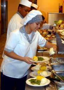 US Navy 061123-N-6247M-008 Culinary Specialist Seaman Ashley Moody, from Tulsa, Okla., scoops mashed potatoes on a plate for a customer during Thanksgiving dinner