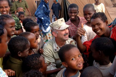 US Navy 061202-F-4925S-062 U.S. Navy. Capt. Kevin Hutcheson, Combined Joint Task Force-Horn of Africa (CJTF-HOA) deputy political advisor, shares a moment with children who are living in a tent city set up by CJTF-HOA