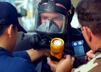 US Navy 061129-N-3285B-033 Seaman Carlos Ramirez and Navy Diver 1st Class William Pauley assist Navy Diver 2nd Class Jason Eppley by adjusting his diving gear before a dive photo