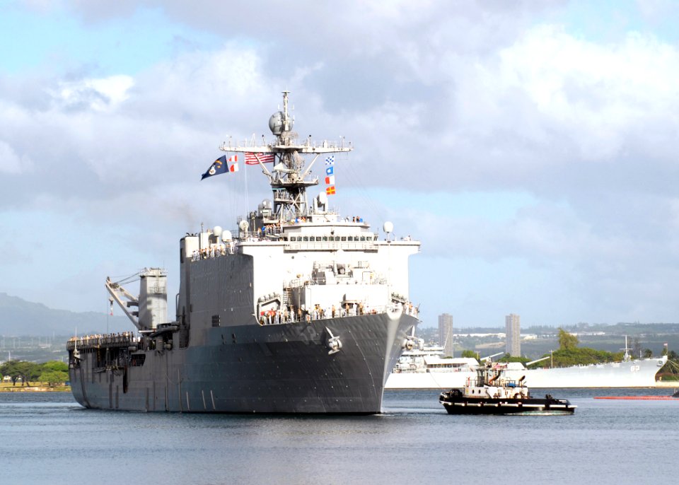 US Navy 061204-N-4965F-004 Sailors aboard dock landing ship USS Pearl Harbor (LSD 52) man the rails as a tugboat assigned to Naval Station Pearl Harbor guides the ship into Pearl Harbor