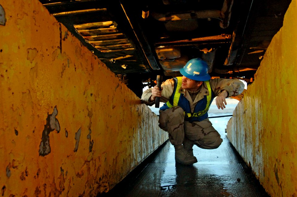 US Navy 061209-N-8148A-024 Customs Border Clearance Agent Quartermaster 3rd Class Christian Moreno, assigned to Navy Customs Battalion Romeo, inspects the undercarriage of a recently sanitized U.S. Army Humvee