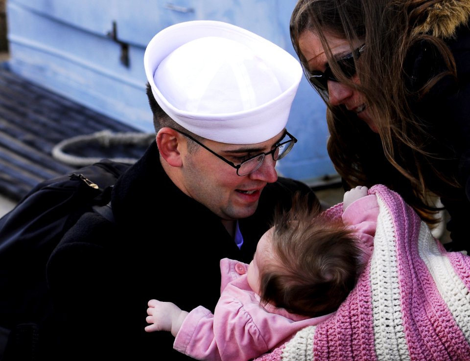 US Navy 061206-N-1831S-378 Boatswain's Mate Seaman David Rumohr holds his newborn child after returning from deployment aboard the amphibious transport dock USS Nashville (LPD 13)