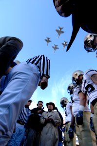 US Navy 061202-N-3642E-129 Secretary of Defense the Honorable Donald H. Rumsfeld, center, readies the coin-toss, as four U.S. Navy F-A-18 Super Hornets conduct a formation fly-over Lincoln Financial Field